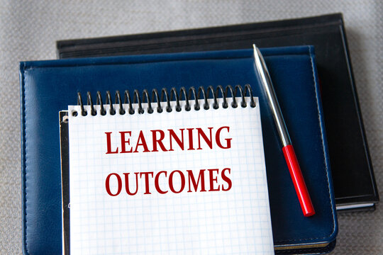 LEARNING OUTCOMES - words in a notebook against the background of books lying on a gray background.