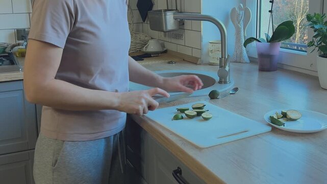 Feijoa fruit being sliced on cutting board. Preparation of fresh healthy food in home kitchen.
