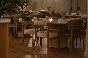 Fototapeta premium Cozy Modern Cafe Interior with Wooden Chairs and Warm Ambient Lighting