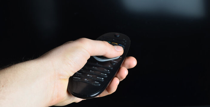 remote control in hand. male hand with a tv remote control turns on the tv.