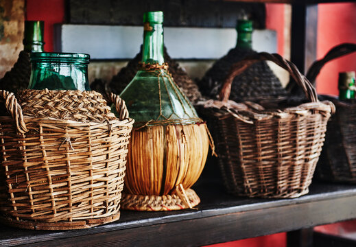 Vintage French demijohn bottle's enclosed in a handwoven wicker basket. Traditionally used to transport wine, spirits or vinegar 
