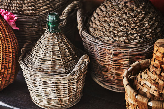 a vintage French demijohn bottle enclosed in a handwoven wicker basket. Traditionally used to transport wine, spirits or vinegar 