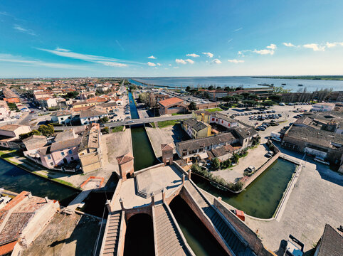 Aerial view of the historic Trepponti bridge and scenic canals surrounded by traditional brick houses in Comacchio, Emilia-Romagna, Italy.