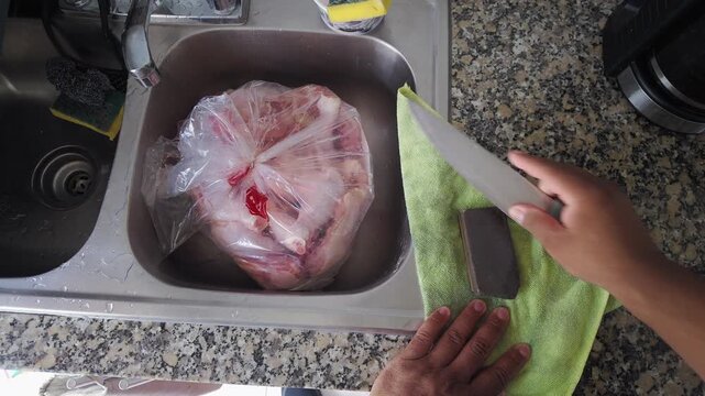 Person sharpening kitchen knife before preparing chicken