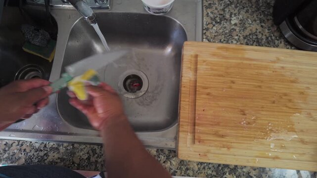 Person washing a kitchen knife in the sink after cooking