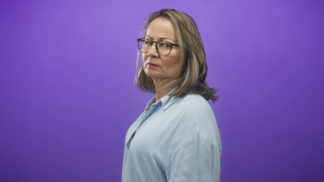 Hispanic woman wearing glasses, face visible, looking sideways against a purple studio backdrop; maturity contemplation.