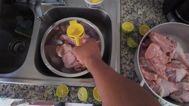 Person squeezing lime juice over raw chicken meat