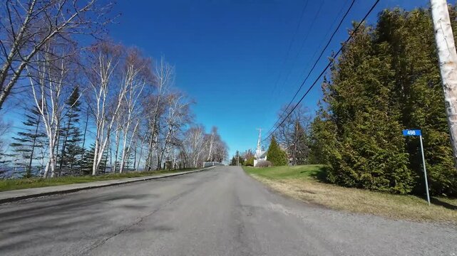 4K dashcam footage driving through a fenced coastal alley past the historic Metis Beach United Church built in 1866 in Metis-sur-Mer, Quebec, Canada.