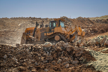 Fototapeta premium A bulldozer moving rocks on uneven ground at a construction site