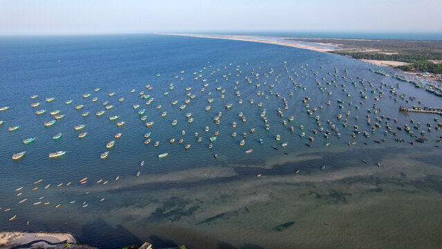 Aerial view of a vast fleet of traditional fishing boats anchored in the calm blue waters of the Arabian Sea near the coastline Thiruvananthapuram, Kerala, India.