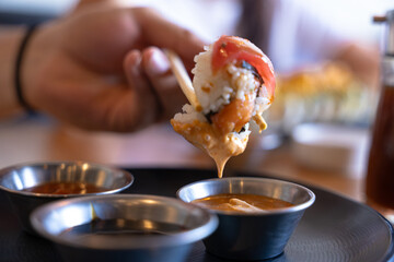 Hand dipping fresh sushi roll into creamy sauce © Fabian Vargas