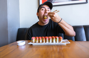 Young man enjoying sushi roll with chopsticks at restaurant © Fabian Vargas