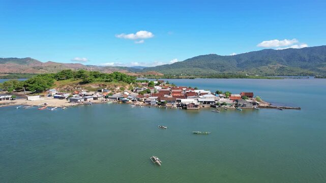Aerial drone footage of old Bajo crowded small village, local wooden and metallic roof houses, fishing boats, with stunning bay behind in quiet sea, in Dompu regency, Sumbawa island, Indonesia