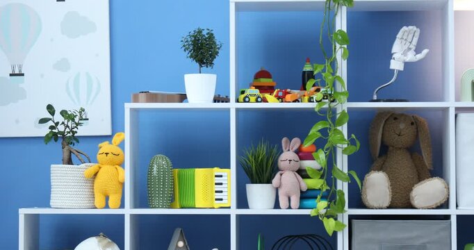 Shelving unit with different toys and decor near blue wall in child's room. Camera moving left