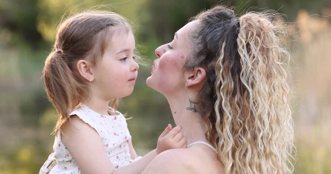 Mother with her cute little daughter in nature on sunny day. Camera moving forward and backwards