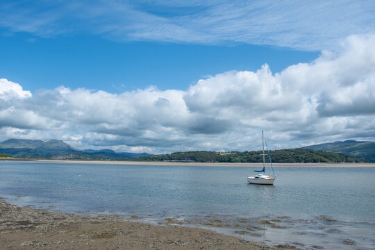 White sailboat anchored in the Glaslyn Estuary at low tide near Borth-y-Gest, Snowdonia, Wales, UK