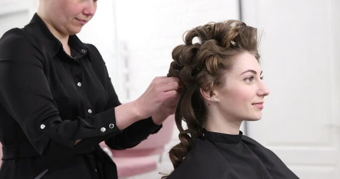 Stylist styling woman's hair in beauty salon