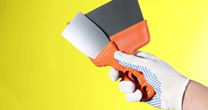 Handyman with putty knives on yellow background, closeup