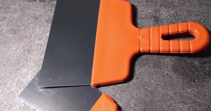 Putty knives on grey table, closeup. Construction tool