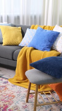 Soft cushions in colorful pillowcases on sofa indoors. Camera moving left