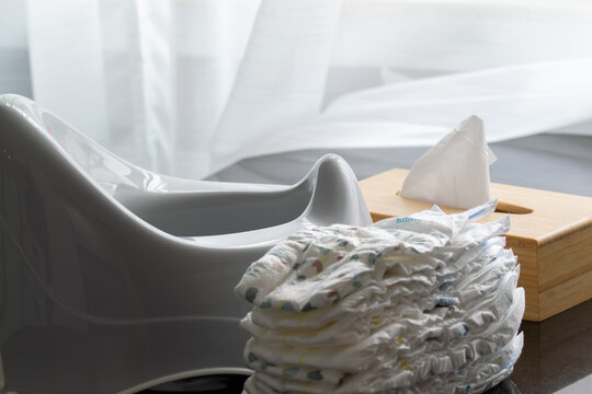 Stack of diapers with a potty and a box of napkins. Baby nappies and potty training concept, highlighting baby products, diaper promotions, or child care