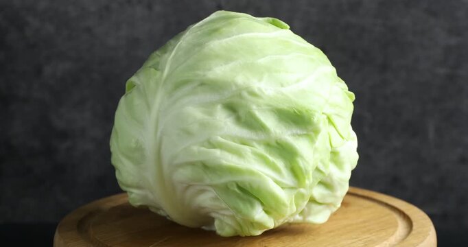 Fresh ripe cabbage on wooden board, rotating