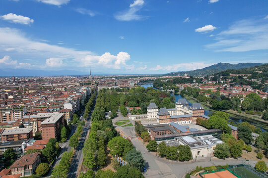 Aerial view of Castello del Valentino surrounded by lush greenery of Parco del Valentino and the Po River with the city skyline and Alps in the distance Torino, Piemonte, Italy.