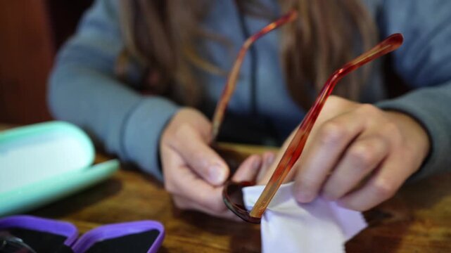 Woman cleaning eyeglasses with microfiber cloth