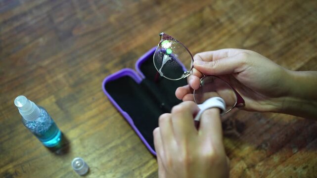 Woman cleaning eyeglasses with spray and microfiber cloth