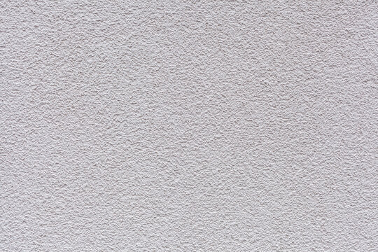 A close-up sample of decorative plaster coating on the walls of a house with a shagreen pattern