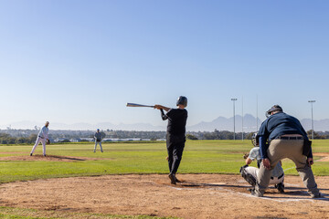 Obraz premium Mature male players, senior catcher in gear watching batter in black helmet swinging bat in box