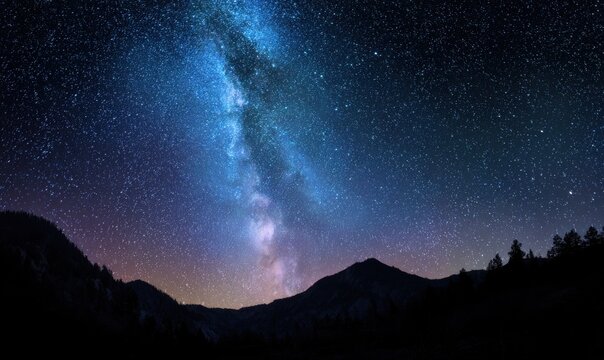 Night sky with bright Milky Way above forested hills and trees