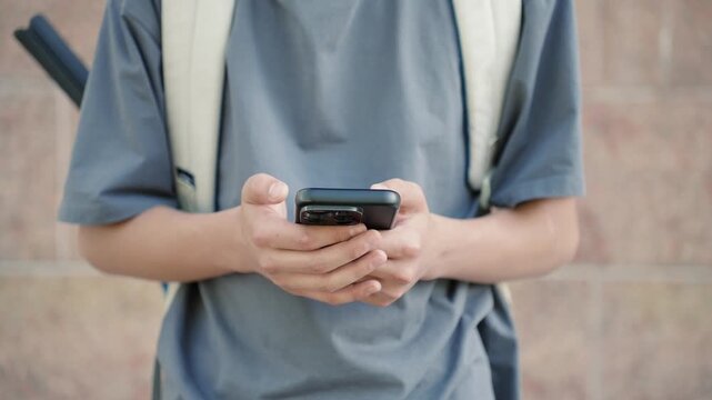 Young male person using smartphone close up while typing message outdoors. Authentic communication, real people, mobile usage and modern digital lifestyle concept.