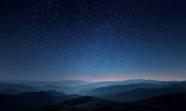 Night sky filled with stars over misty mountain ridges