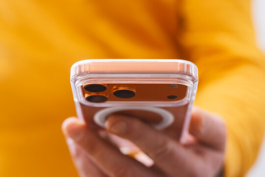 Close-up of hand holding rose gold smartphone back view with triple camera lens and transparent case. Concept for mobile technology and modern communication.