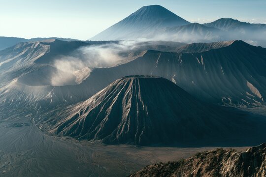 Active volcanic peaks rising from mist in a rugged caldera at dawn with dramatic morning light for adventure travel and tourism marketing