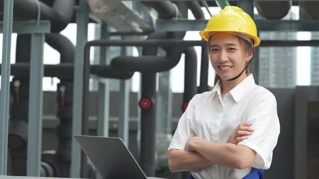 A professional female engineer wearing a yellow hardhat uses a tool to perform a technical electrical control panel audit and facility maintenance.