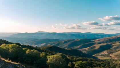 Obraz premium Rolling hills and mountains under a blue sky with scattered clouds and lush green trees