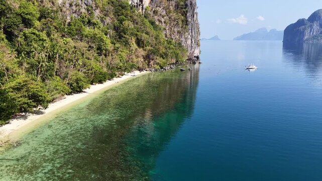 A beautiful beach is fringed by a coral reef on a remote island in El Nido, Philippines. This scenic area of Palawan is a popular vacation destination due to its reefs, beaches, and rock islands.