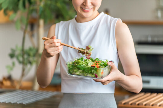 A young woman in sportswear eating a diet menu.