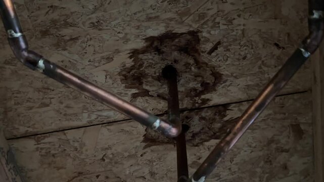 Water damage around interior basement pipes in unfinished residential construction space