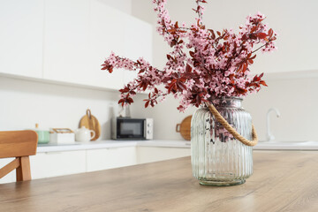 Fototapeta premium Vase with blooming tree branches on table in stylish kitchen