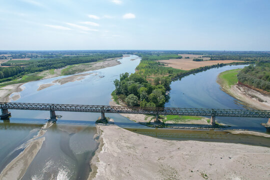 Aerial view of Ponte della Becca spanning the confluence of the Po and Ticino rivers with sandy banks and lush vegetation under a clear sky Linarolo, Lombardia, Italy.