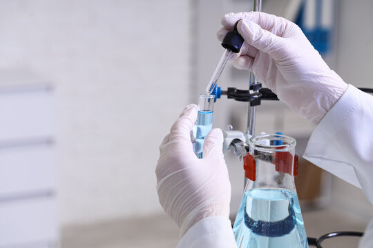 Female scientist's hands dropping water sample into test tube in laboratory, closeup