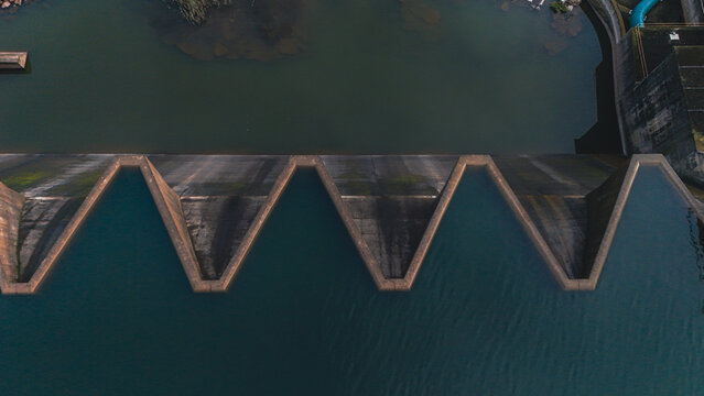 Aerial view of a massive concrete dam wall with a unique labyrinth spillway and dark water in Mooi River, KwaZulu-Natal, South Africa.