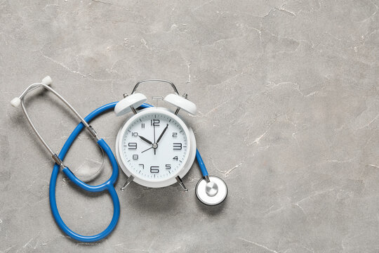 Alarm clock with stethoscope on grunge background