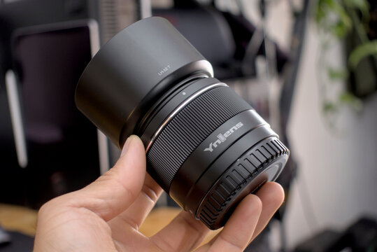 Zapopan Jalisco, Mexico - May 14, 2025: Hand holding Yongnuo lens with LH-52 T hood, lenshood concept