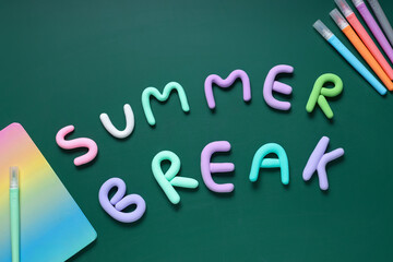 Fototapeta premium Composition with text SUMMER BREAK made of play dough, markers and notebook on green background