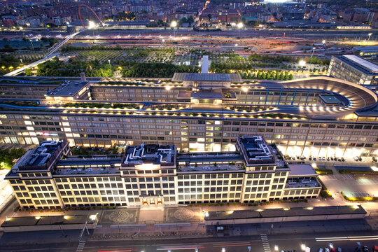 Aerial view of the historic Lingotto building featuring its iconic rooftop test track illuminated at night in Turin, Piedmont, Italy.