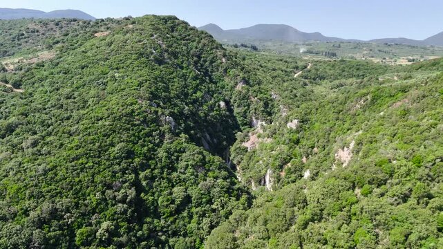 Aerial View of Polylimnio Waterfall Canyon in Peloponnese, Greece, with Green Forested Cliffs, Rocky Gorge and Mediterranean Mountain Landscape